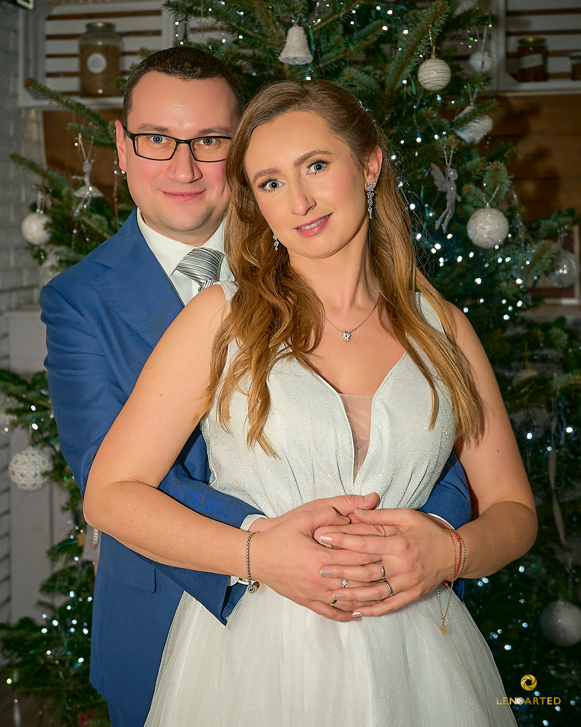 Panna młoda i pan młody przytuleni w świątecznej atmosferze – portret ślubny przy choince.