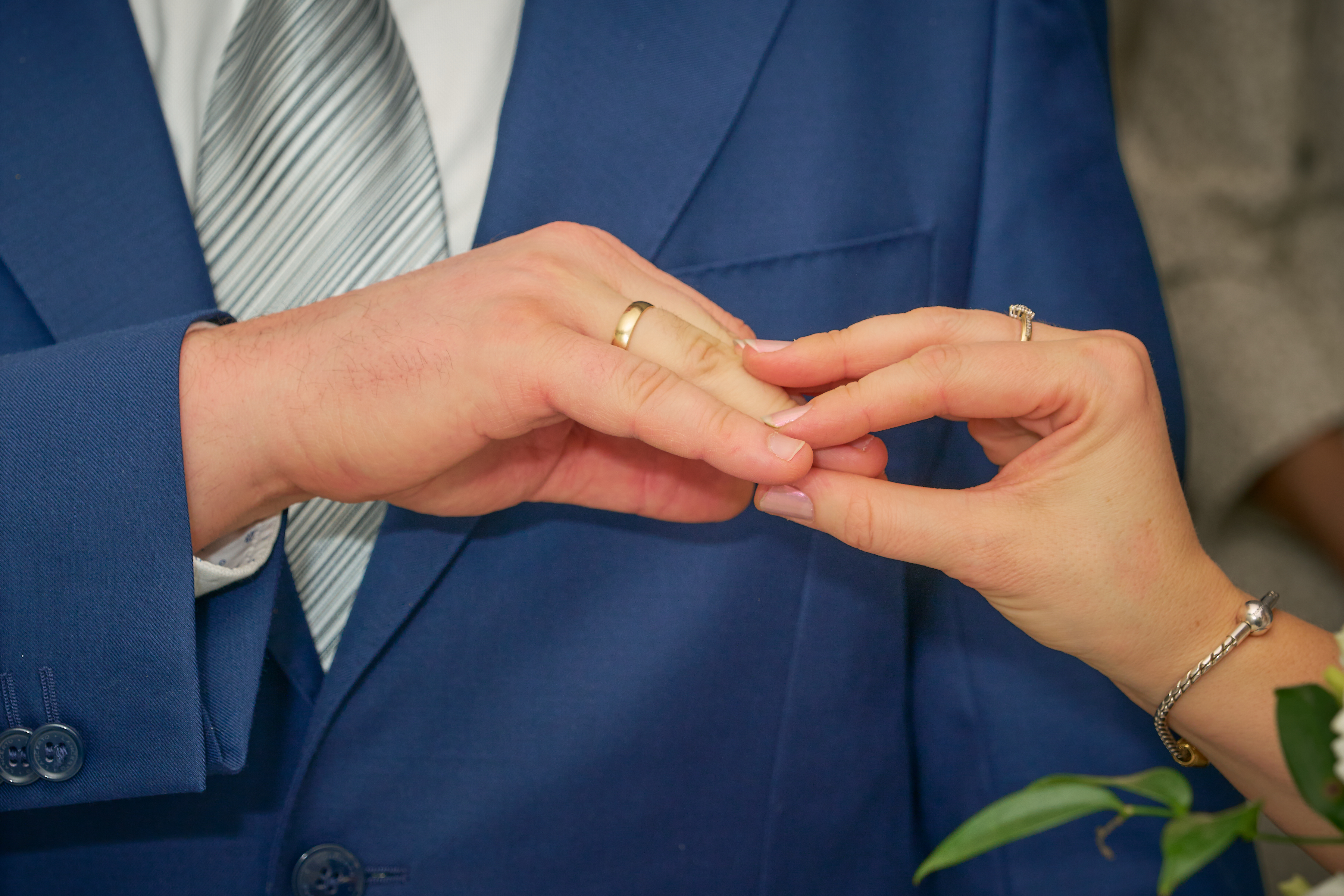 Moment zakładania obrączki podczas ceremonii ślubnej, zbliżenie na dłonie pary młodej.