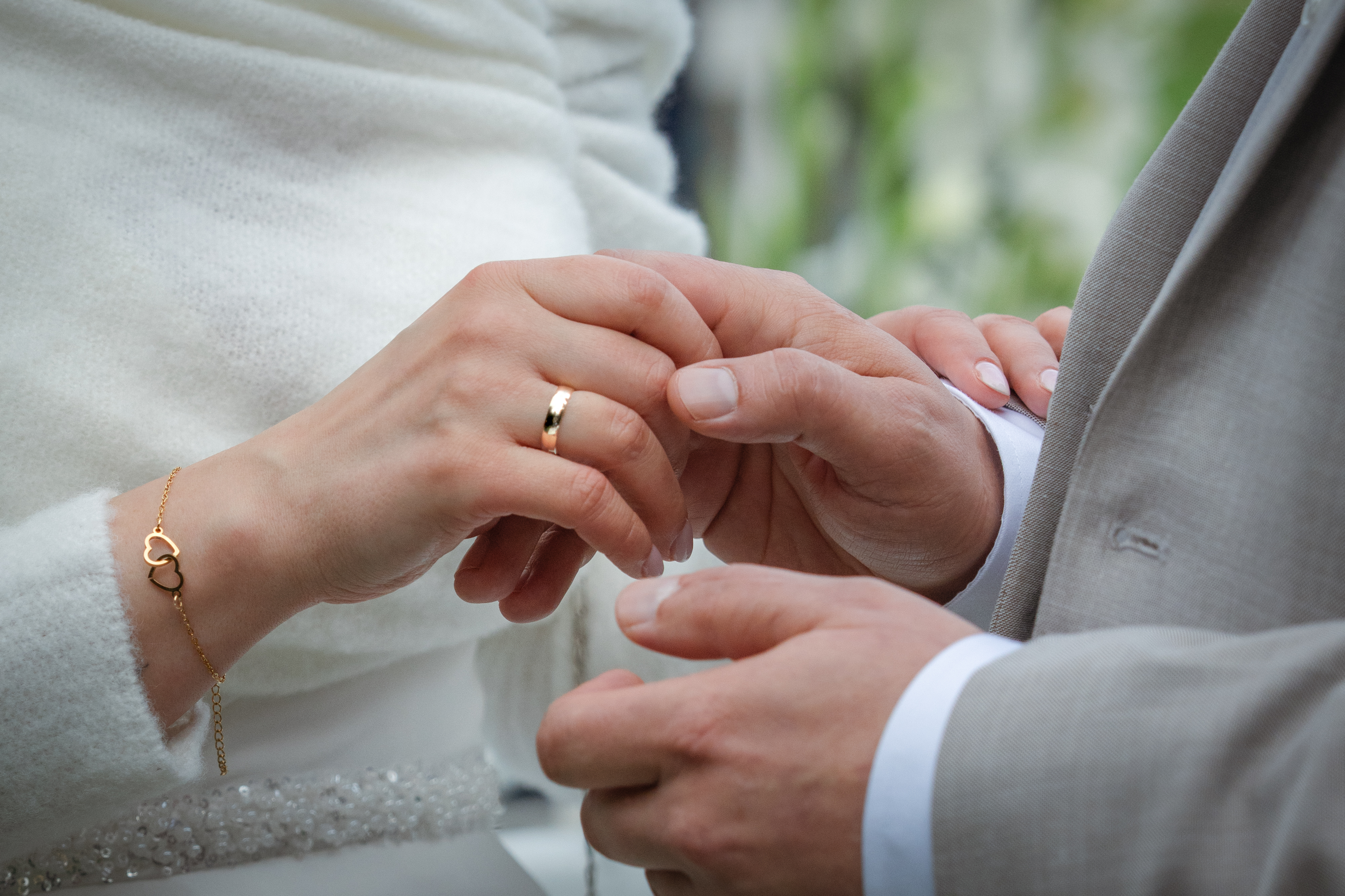 Zakładanie obrączki podczas ceremonii ślubnej, zbliżenie dłoni.