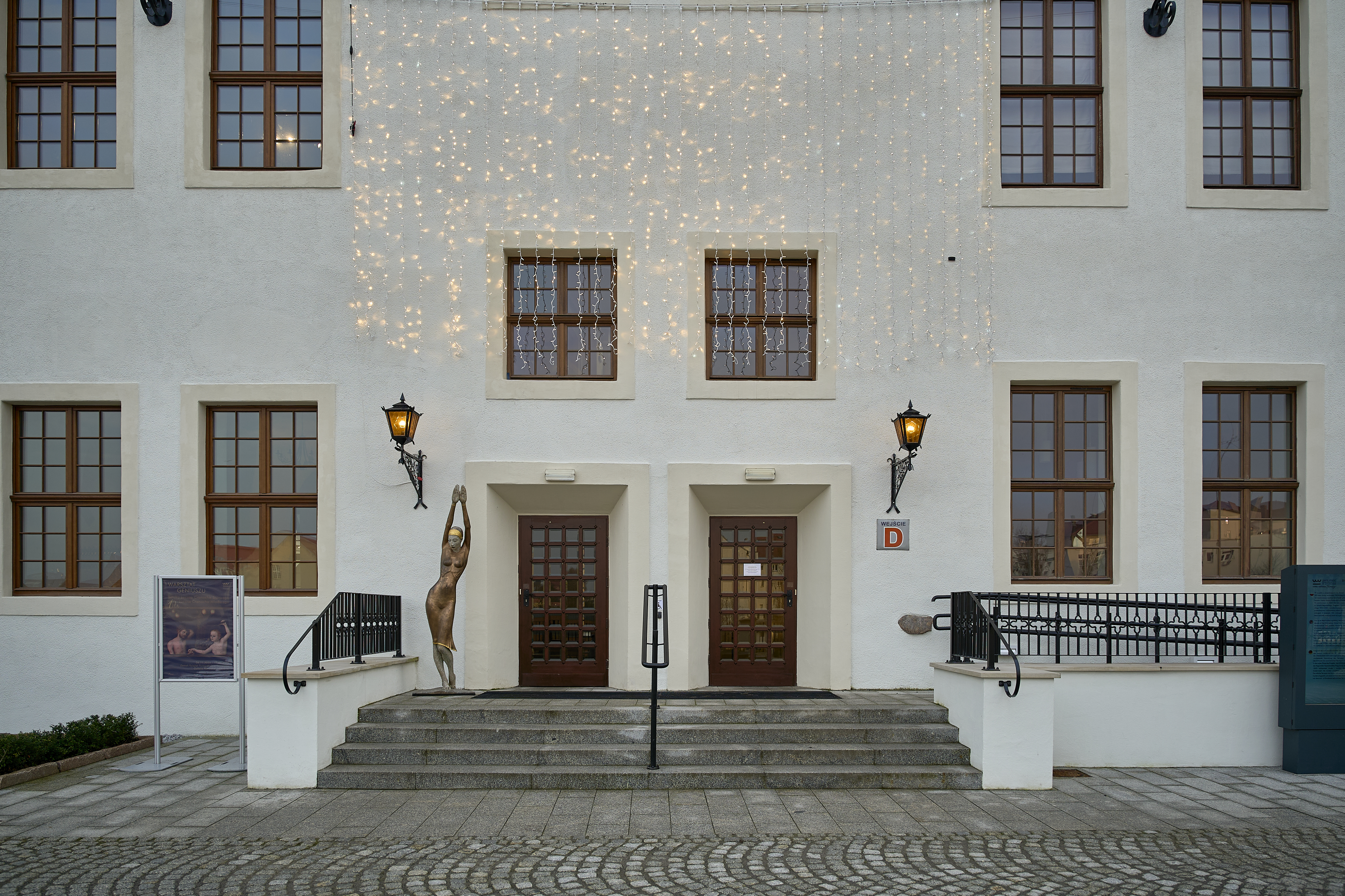 Elewacja historycznego budynku fotografowana obiektywem Sigma 24–70 mm f/2.8 DG DN Art przy ogniskowej 24 mm. Opis / caption. Test szerokiego kąta (24 mm): geometria elewacji, kontrola perspektywy i równomierna ostrość w całym kadrze.